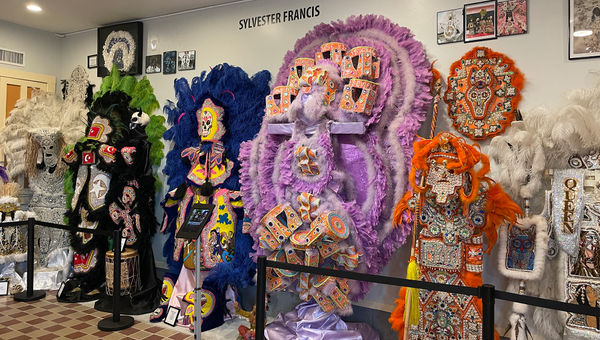 A collection of Mardi Gras Indian suits from various tribes on display.