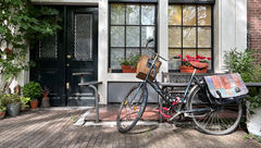 A lone bicycle resting against the front porch of a canal house in Amsterdam’s Haarlemmerstraat neighborhood.